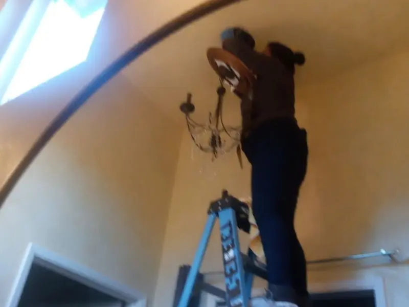 Electrician installing a chandelier in a Fruitland residence